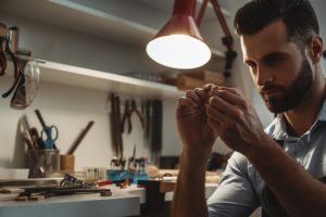 Perfection. Close up of young male jeweler looking and inspecting a ring